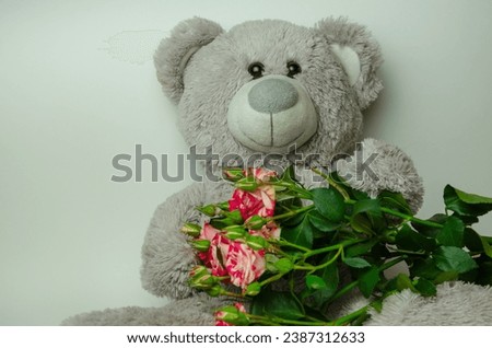 Gray bear toy with bouquet of roses. High quality photo