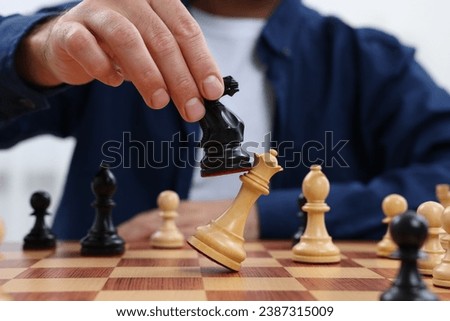 Man moving knight on chessboard indoors, closeup