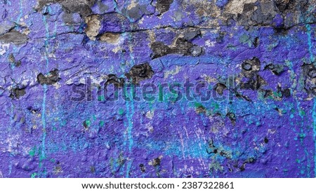 Dark purple old crumbling concrete wall with black spots and cyan paint splashed.