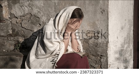 Misery lost feel mourn weep mood young lone holy jew maid slave teen lady Mary sit ask god Jesus Christ faith hope. Old retro roman history biblical adult human shame abuse white islam home text space Royalty-Free Stock Photo #2387323371