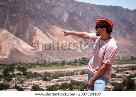 Tourist pointing at the beautiful colorful mountains in Jujuy, Argentina. Tourist in the north of Argentina. Wonderful colorful mountains in the Quebrada de Humahuaca, Argentina  Royalty-Free Stock Photo #2387324109
