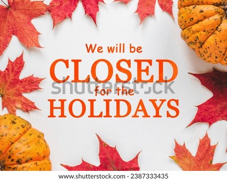 Signboard with the inscription We will be closed for the holidays. Bright pumpkins, tree leaves, red berries and colorful flowers lying on an empty table. Close-up, indoors. Studio shot