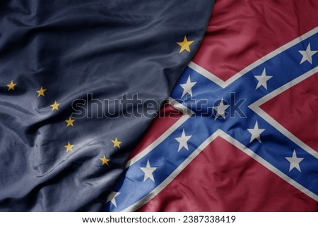 big waving colorful confederate jack flag and flag of alaska state . macro