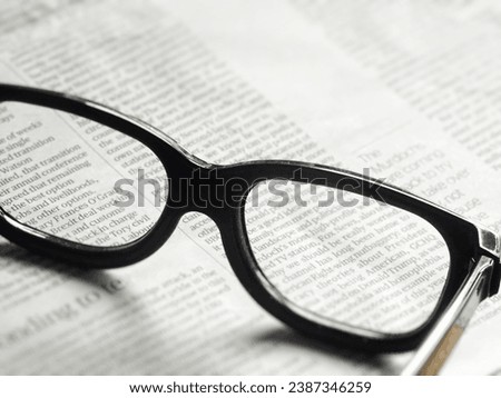 Close up of a pair of reading glasses on a daily newspaper. concept of information, knowledge and reading the news Royalty-Free Stock Photo #2387346259