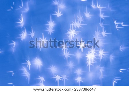 Christmas or New Year abstract magic lights background, white stars bokeh on blue as winter holiday backdrop. Xmas mood aesthetic photo, blurred effect, celebration illumination, winter starry sky