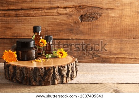 Different cosmetic products and beautiful calendula flowers on wooden table, space for text