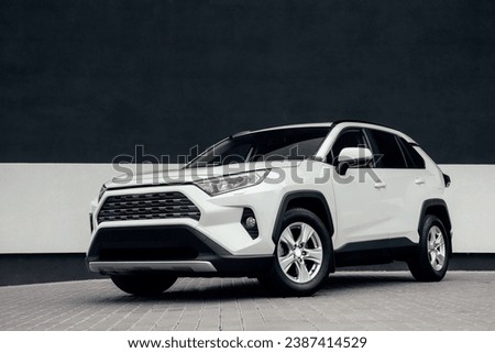 A modern urban SUV-crossover in white color, with beautiful wheels and a large chrome grille. Exterior details.