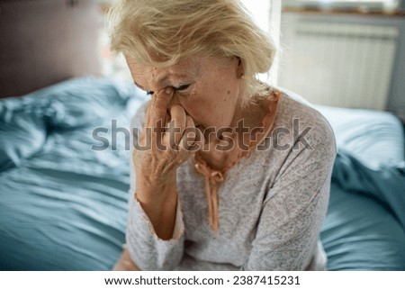Worried Senior Woman Sitting in Bed Royalty-Free Stock Photo #2387415231