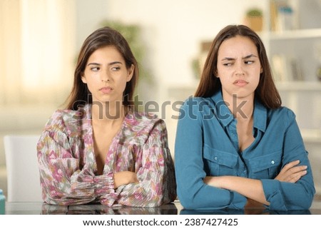 Front view portrait of two angry friends ignoring each other at home Royalty-Free Stock Photo #2387427425