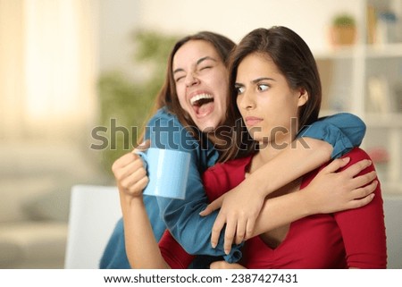 Excited woman embracing a perplexed friend at home Royalty-Free Stock Photo #2387427431