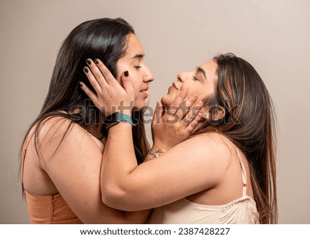 Young women looking at each other in love on pastel background.
