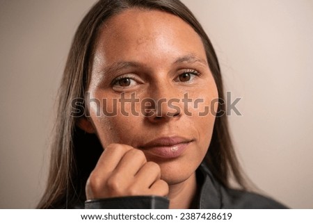 Close portrait. Young woman with hand on face looking at camera on pastel background.