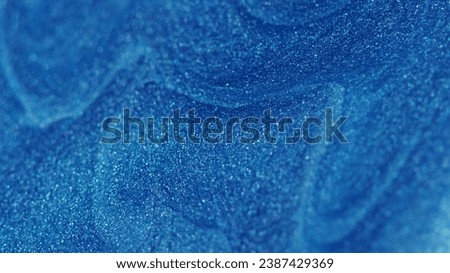 Glitter fluid. Paint flow. Enamel drip. Defocused shiny shimmering blue color wet particles texture ink wave creative art abstract background with free space.