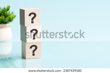 three question marks - text on wooden blocks on blue background. business concept.
