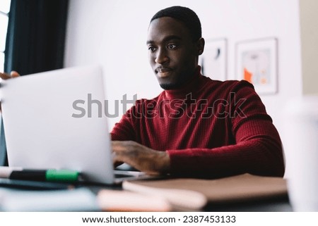 Calm black man surfing netbook in office