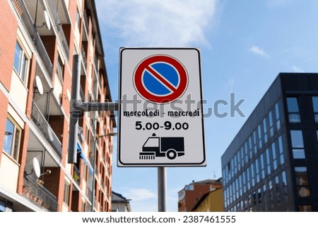 Bilingual traffic sign in the Aosta Valley, Italy with information that the street sweeper runs between 5 and 9 on Wednesdays. There is a restricted parking ban. Road sign in Italian and French.