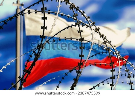 Barbed wire, Flagpole with Russian flag against sky in defocus, 3d rendering. Concept: international sanctions, aggressor country, totalitarian regime, iron curtain, socialism camp. Royalty-Free Stock Photo #2387475599