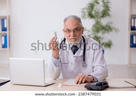 Old male doctor suggesting pills in the clinic Royalty-Free Stock Photo #2387479031