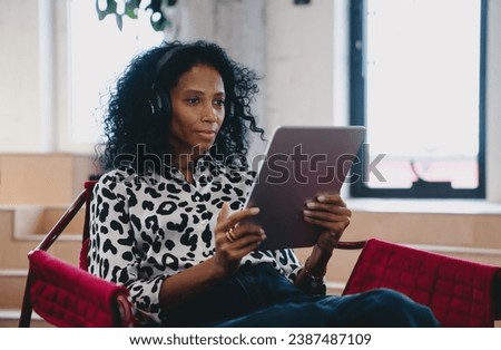 Creative Black female content strategist reviewing social media analytics on tablet, in a modern workspace, reflecting engagement and strategic thinking