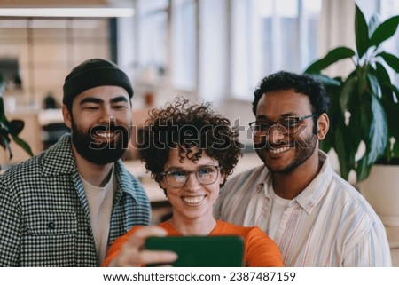 Cheerful multiethnic colleagues taking selfie in office