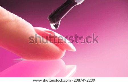 Applying Nail polish, pink shellac UV gel, varnish, manicure process concept in beauty salon. Transparent top coat drop on brush. Over pink background. Application of nail polish Royalty-Free Stock Photo #2387492239