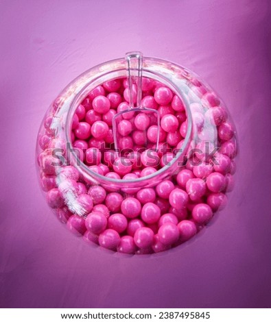 Close up of pink gumballs in a glass bowl with a plastic scoop  Royalty-Free Stock Photo #2387495845