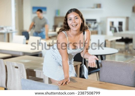 Girl customer touching table in the furniture store before the buying