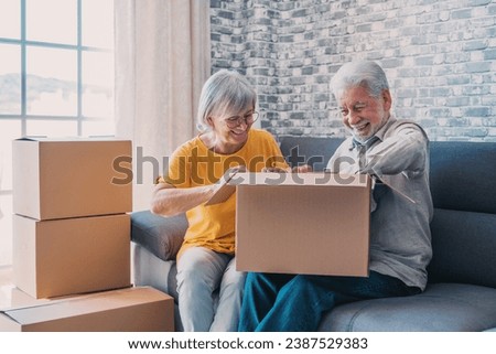 Relaxed mature married couple in love resting on couch among paper cardboard boxes, taking break, pause, hugging, talking, enjoying being in new home. Real estate concept Royalty-Free Stock Photo #2387529383