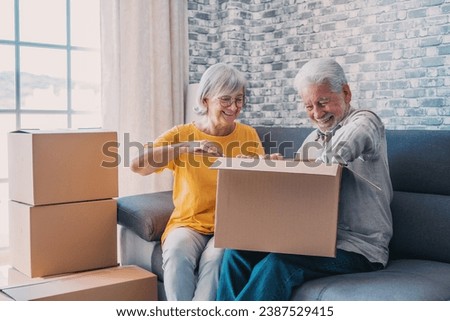 Relaxed mature married couple in love resting on couch among paper cardboard boxes, taking break, pause, hugging, talking, enjoying being in new home. Real estate concept Royalty-Free Stock Photo #2387529415