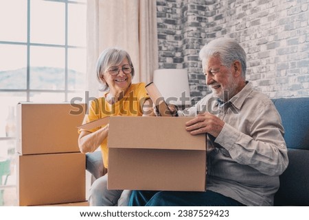 Relaxed mature married couple in love resting on couch among paper cardboard boxes, taking break, pause, hugging, talking, enjoying being in new home. Real estate concept Royalty-Free Stock Photo #2387529423