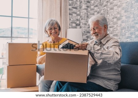 Relaxed mature married couple in love resting on couch among paper cardboard boxes, taking break, pause, hugging, talking, enjoying being in new home. Real estate concept Royalty-Free Stock Photo #2387529443