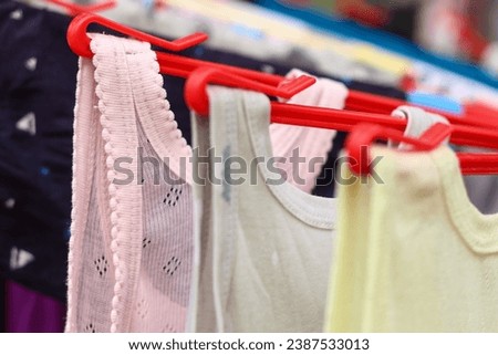 A toddler's undershirt is being dried using a round hanger