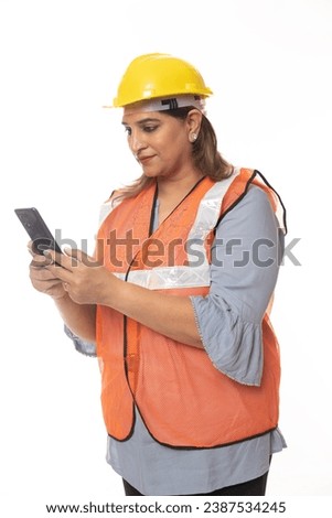 Female constructor using cell phone. Wearing hardhat and worker apron while isolated on white studio background.