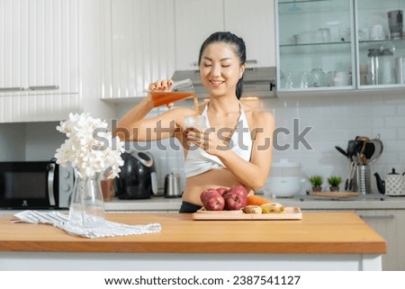 A healthy Asian woman in exercise clothes Is happily cooking a healthy meal in her home kitchen in the morning. Healthy care concept, Healthy fruits every day. Royalty-Free Stock Photo #2387541127