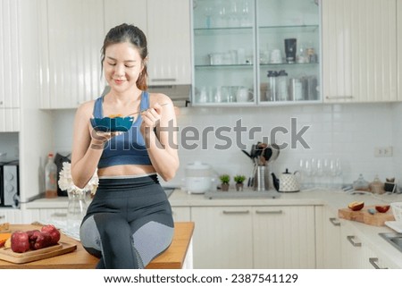A healthy Asian woman in exercise clothes Is happily cooking a healthy meal in her home kitchen in the morning. Healthy care concept, Healthy fruits every day. Royalty-Free Stock Photo #2387541129