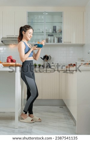 A healthy Asian woman in exercise clothes Is happily cooking a healthy meal in her home kitchen in the morning. Healthy care concept, Healthy fruits every day. Royalty-Free Stock Photo #2387541135