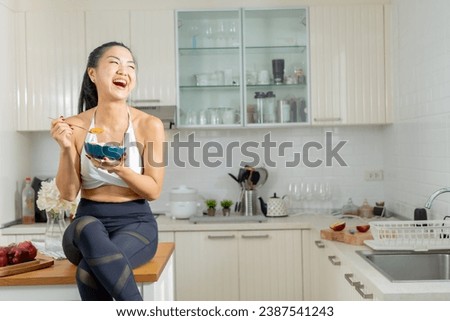 A healthy Asian woman in exercise clothes Is happily cooking a healthy meal in her home kitchen in the morning. Healthy care concept, Healthy fruits every day. Royalty-Free Stock Photo #2387541243