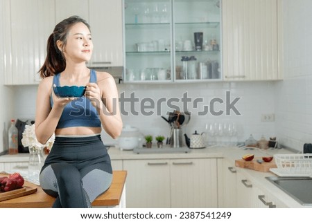 A healthy Asian woman in exercise clothes Is happily cooking a healthy meal in her home kitchen in the morning. Healthy care concept, Healthy fruits every day. Royalty-Free Stock Photo #2387541249