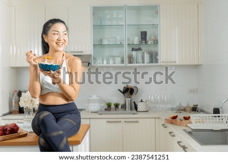 A healthy Asian woman in exercise clothes Is happily cooking a healthy meal in her home kitchen in the morning. Healthy care concept, Healthy fruits every day. Royalty-Free Stock Photo #2387541251