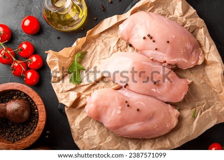 Raw chicken breast meat and spices for its preparation on a black background, top view. High quality photo