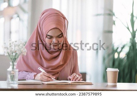 An Asian Muslim university student is doing homework at home