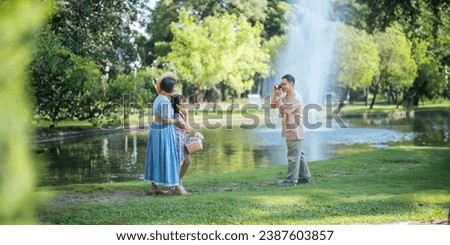 Grandpa takes pictures of granddaughter and grandma with his in park on sunny day happiness. concept grandparent and grandchild family lives together happy