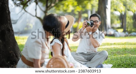 Grandpa takes pictures of granddaughter and grandma with his in park on sunny day happiness. concept grandparent and grandchild family lives together happy
