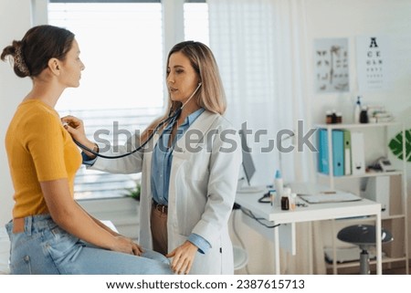 Doctor listening girl's breathing, heartbeats using a stethoscope. Teenage girl visiting paediatrician for annual preventive physical examination. Concept of preventive health care for adolescents Royalty-Free Stock Photo #2387615713
