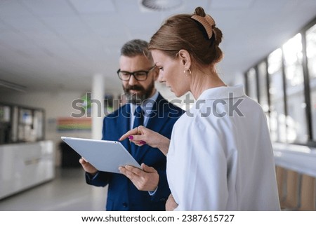 Pharmaceutical sales representative talking with female doctor in medical building. Hospital director consulting with healthcare staff. Royalty-Free Stock Photo #2387615727