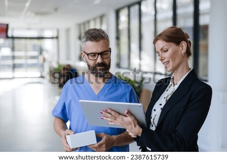 Pharmaceutical sales representative talking with doctor in medical building. Ambitious female sales representative presenting new medication. Woman business leader. Royalty-Free Stock Photo #2387615739