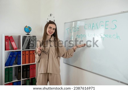 Young caucasian teacher giving lesson for english grammar near whiteboard in classroom. Learning concept Royalty-Free Stock Photo #2387616971