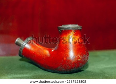 Old smoking pipe on a green tablecloth with a red background .  Pipe for smoke weathered by years of use