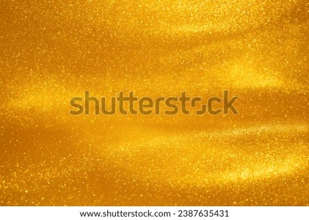 Glittering flows of gold particles in fluid. Various stains and overflows of gold particles in liquid with yellow tints. Abstract shimmering background.