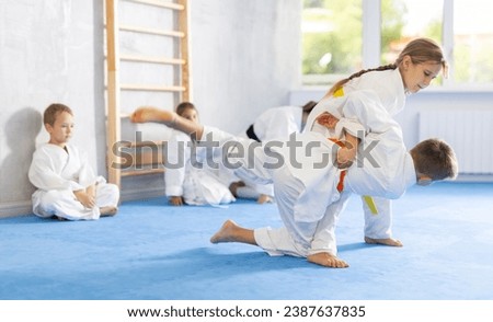 Engrossed sportsmen boys and girls in pair conduct training battle in oriental fighting technique. School of martial arts. Reinforcement strength of mind and body. Sport to max Royalty-Free Stock Photo #2387637835